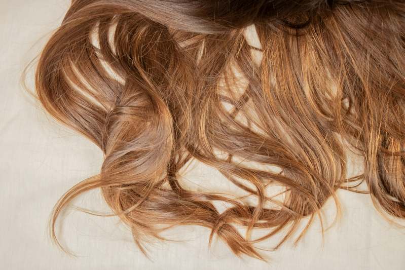 Woman creating a soft, voluminous hair bun with hands and decorative pins