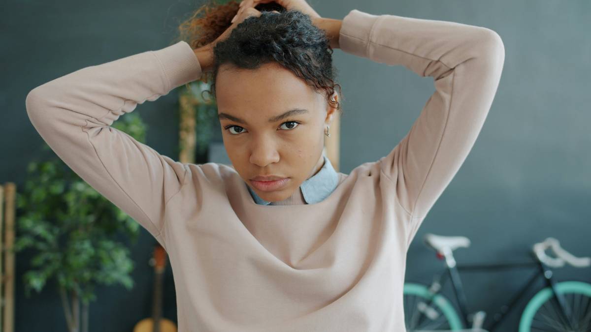 Woman creating Quick Updos with loose hair bun using satin scrunchie